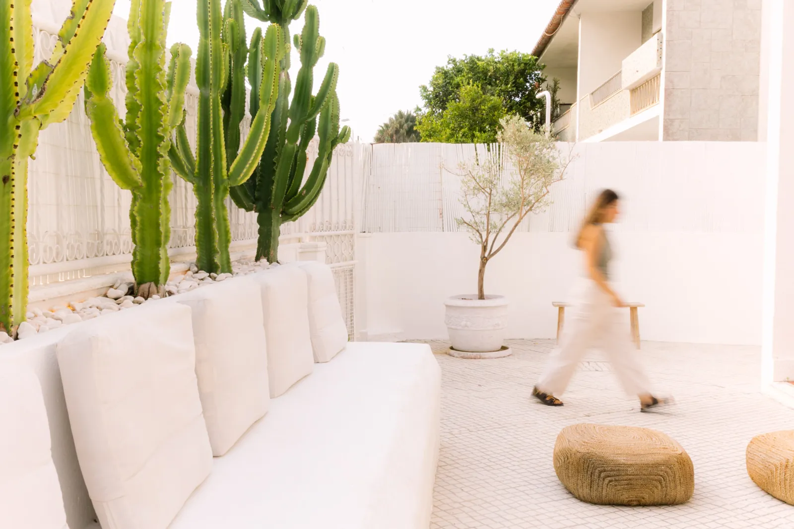 Casa Caparica patio with white sofa, tall cacti and jute poufs